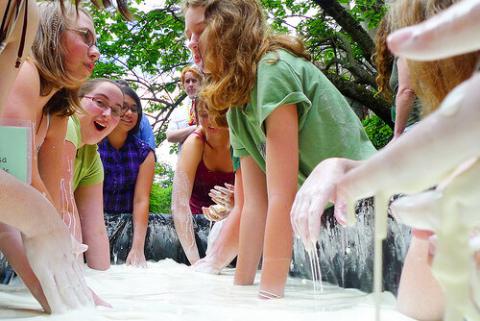 A group of girls dip their hands in Oobleck.